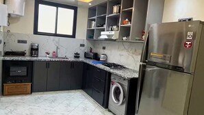 A modern kitchen with a stainless steel refrigerator, built-in oven, and a washing machine.
