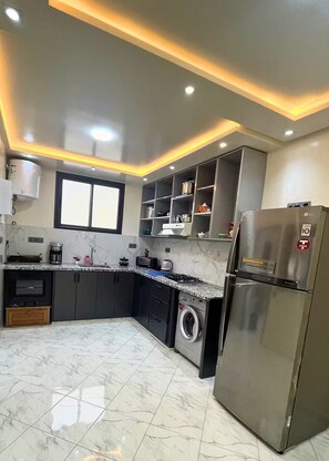 A modern kitchen with a stainless steel refrigerator, built-in oven, and a washing machine. - Private Full Home in Agadir - Families & Groups (Agadir)