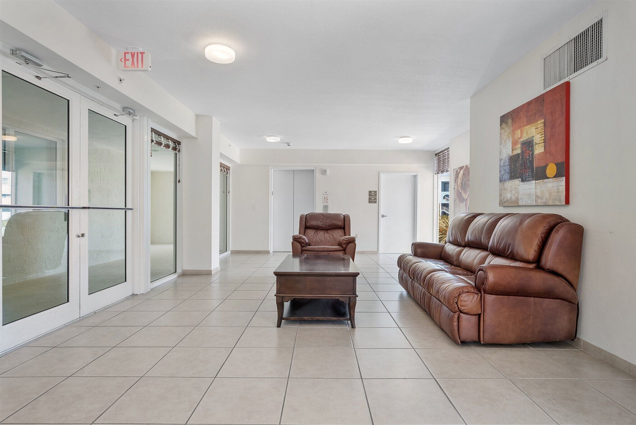A spacious lobby with a leather sofa, a coffee table, and a leather chair.