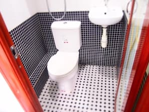 Une salle de bain avec des toilettes blanches, un lavabo blanc et un sol carrelé.