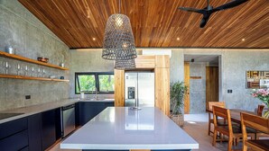 Een moderne keuken met een centraal eiland, houten plafond en een hangende lamp.