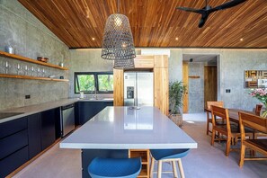 A modern kitchen with a central island, wooden ceiling, and a hanging light fixture. - Private Vacation Home in Tamarindo! Sleeps 6 (Tamarindo)