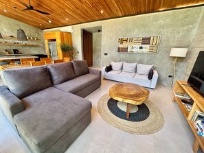 Una sala de estar moderna con un sofá modular gris, una mesa de centro redonda y un sofá blanco con cojines.