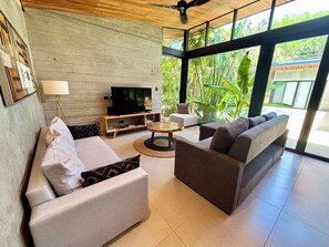Ein modernes Wohnzimmer mit einer Couch, einem Sessel, einem Couchtisch und einem Fernseher.
