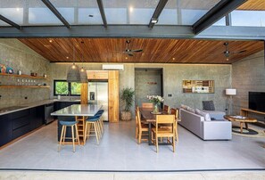 A modern kitchen with a central island, dining area with wooden furniture, and a living space with a sofa and TV. - Private Vacation Home in Tamarindo! Sleeps 6 (Tamarindo)