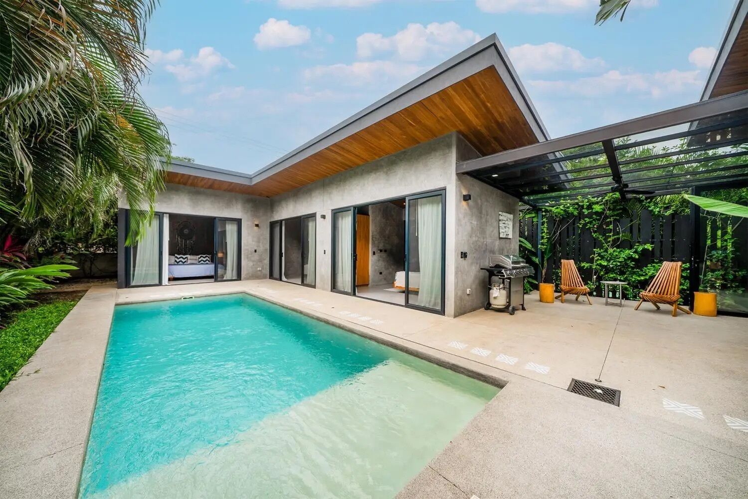 Ein modernes Haus mit Swimmingpool, Schiebetüren und Sitzgelegenheit im Freien.