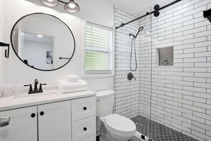 A modern bathroom with a white sink, toilet, and shower. - Stylish, Bright 3BR Retreat Near Downtown ATL (Atlanta)