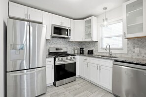 A modern kitchen with stainless steel appliances, white cabinetry, a gas stove, and a built-in oven. - Stylish, Bright 3BR Retreat Near Downtown ATL (Atlanta)