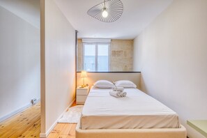 Ein kleines, modernes Schlafzimmer mit einem Einzelbett, einer Nachttischlampe und einer außergewöhnlichen Deckenleuchte.