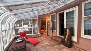 A sunroom with a curved glass ceiling, a seating area with red cushions, and a decorative light fixture.