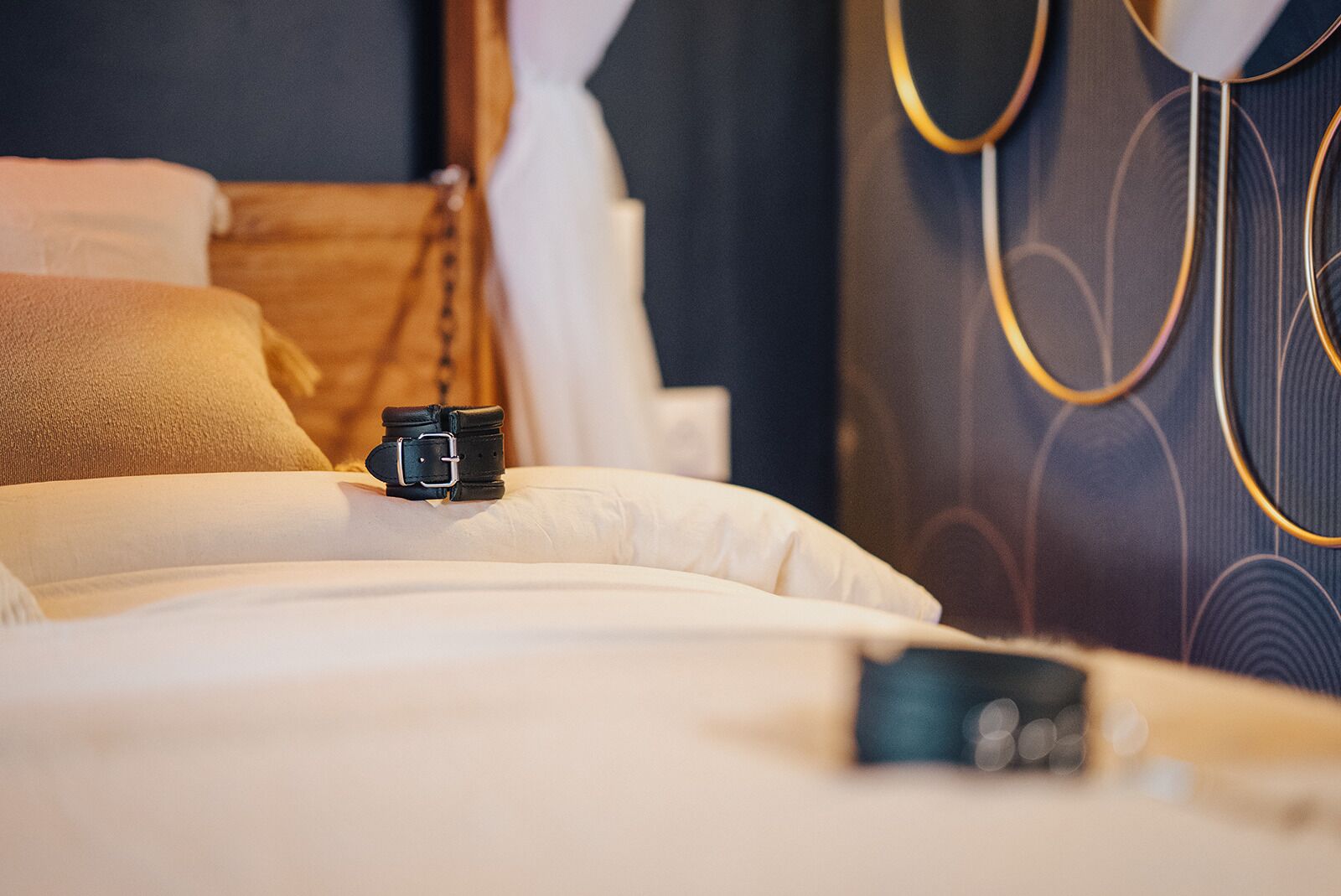 Ein ordentlich gemachtes Bett mit Kamera, Kissen und einem Kopfteil mit kreisförmigem Design.