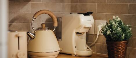 Una encimera de cocina con una tetera, una cafetera y una planta en maceta.