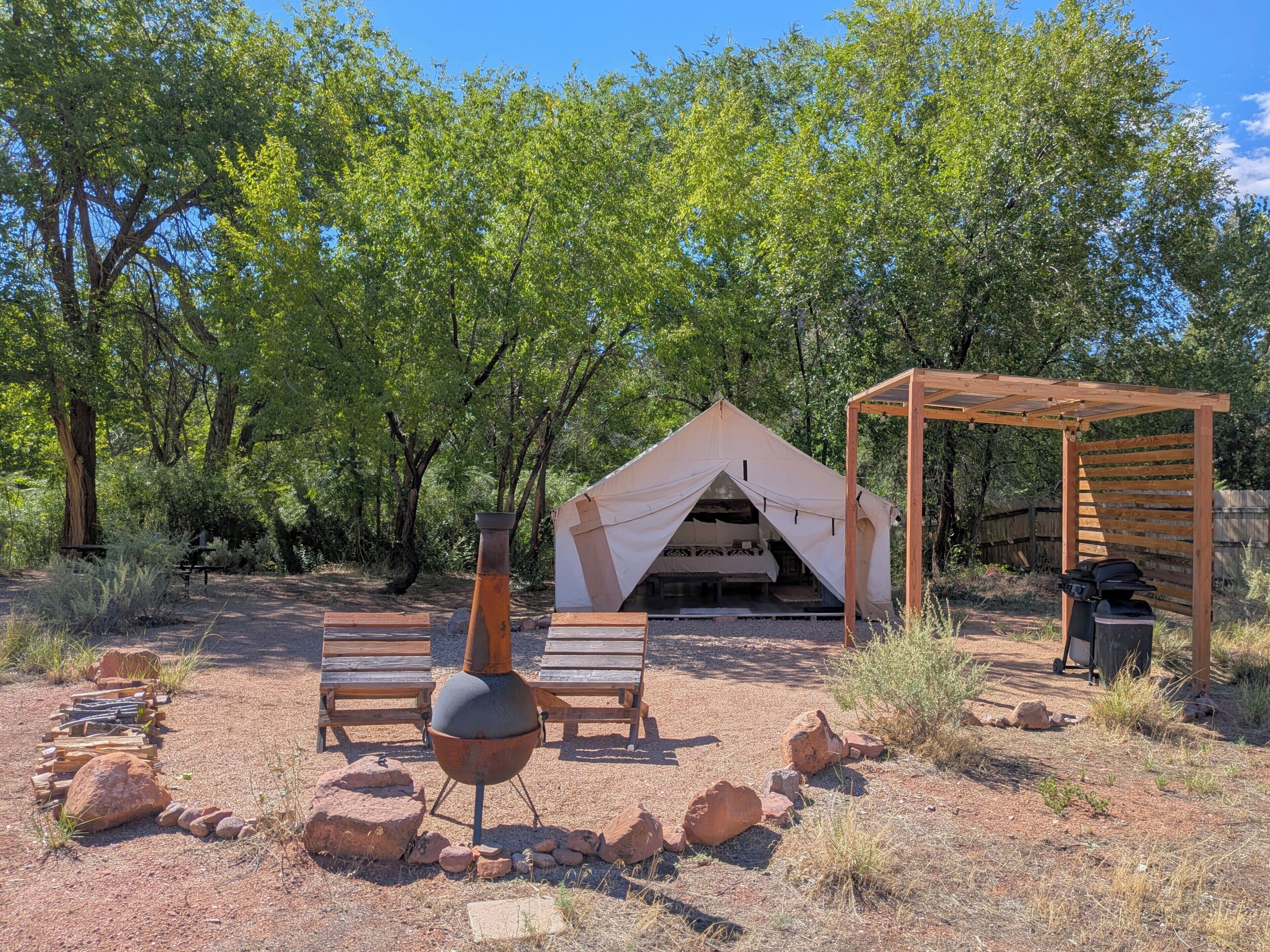 A campsite with a tent, a grill, and seating area.
