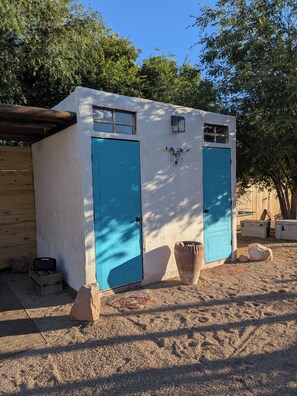 Un pequeño edificio rústico con dos puertas azules y una cabeza de toro decorativa.