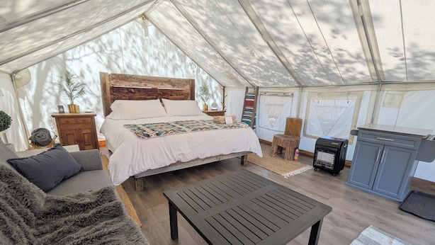 Alojamiento con carpa, que incluye cama, sofá, mesa y kitchenette.