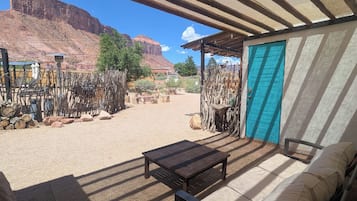 A desert landscape with a covered outdoor seating area featuring a sofa and a table.