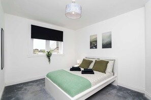 Et soveværelse med en seng, et vindue med udsigt, en hængende plante og en loftlampe.