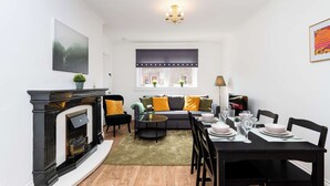 Un salon moderne avec une cheminée, un canapé, une table à manger et des chaises.