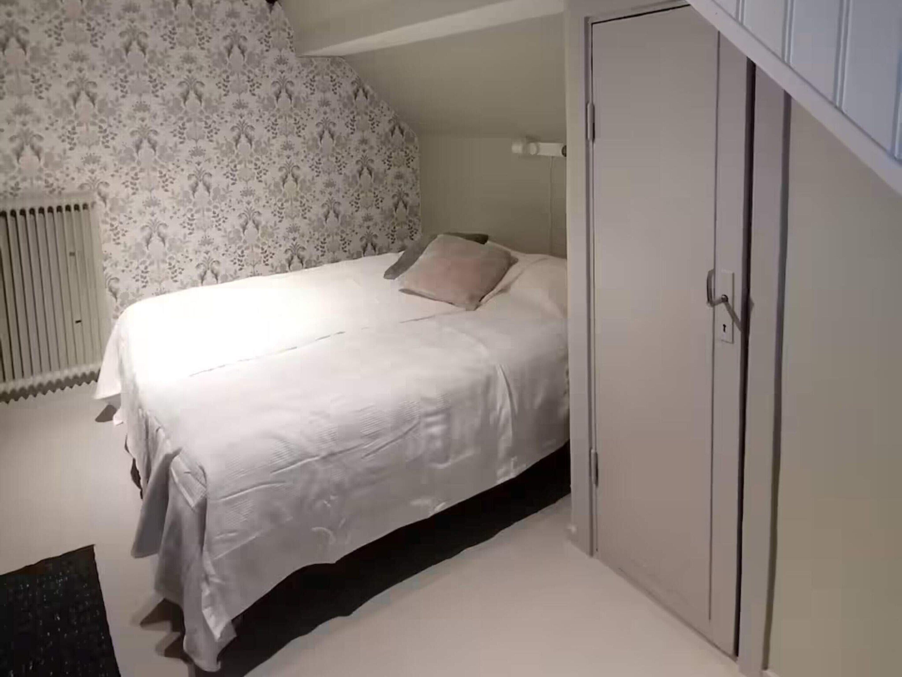 A bedroom with a bed, a wardrobe, and a radiator.