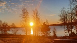 A sunset over a body of water with trees and a bridge. - 5 Star Holiday Home in Skattungbyn Orsa (Orsa)