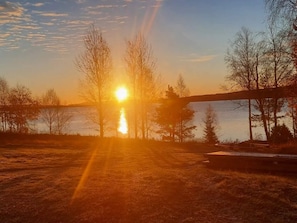 A sunset over a body of water with trees and a bridge. - 5 Star Holiday Home in Skattungbyn Orsa (Orsa)