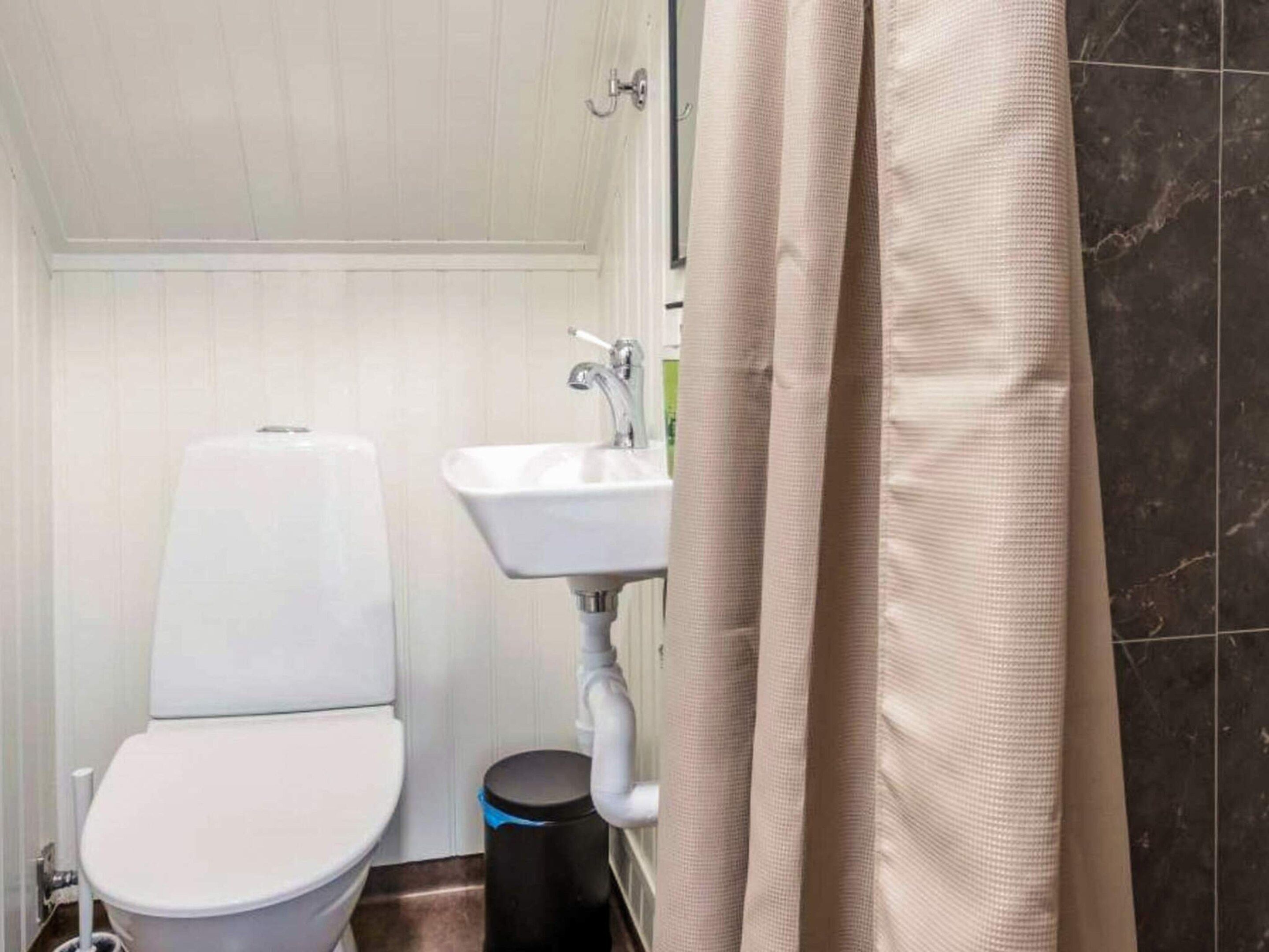 A bathroom with a toilet, sink, and shower curtain.