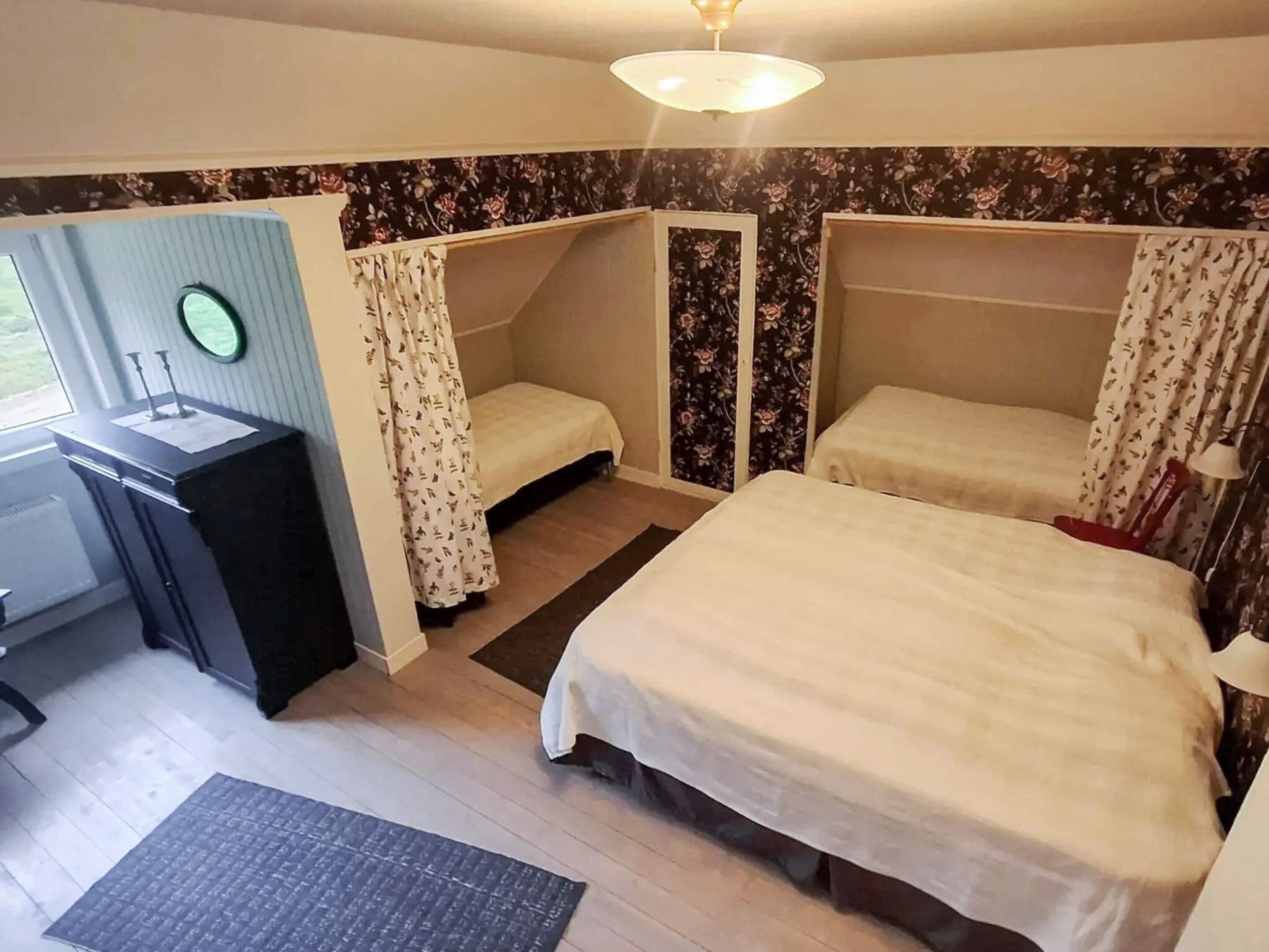 A room with a desk, two beds, a small table, and a chair.