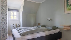 A bedroom with a bed, a chair, a radiator, a window, and a wall-mounted light fixture. - 5 Star Holiday Home in Skattungbyn Orsa (Orsa)