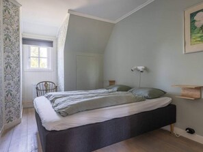 A bedroom with a bed, a chair, a radiator, a window, and a wall-mounted light fixture. - 5 Star Holiday Home in Skattungbyn Orsa (Orsa)