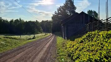 A rural road with a wooden fence and a barn.