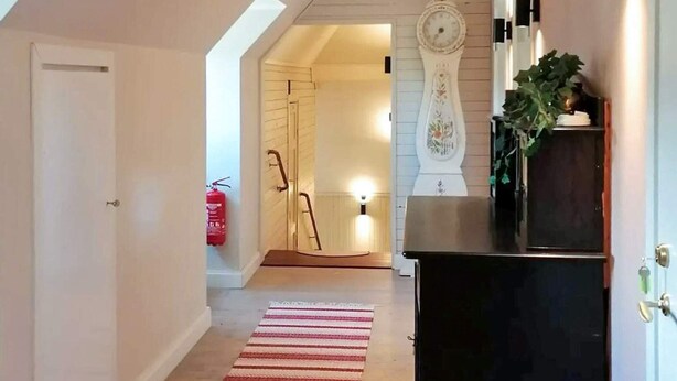 A hallway with a striped rug, a clock, and a fire extinguisher. - 5 Star Holiday Home in Skattungbyn Orsa (Orsa)