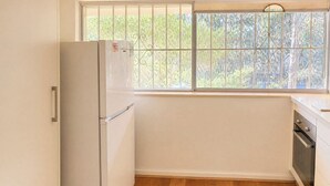 Eine Küche mit Kühlschrank, Backofen und einem Fenster mit Blick auf Bäume.