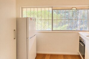 Eine Küche mit Kühlschrank, Backofen und einem Fenster mit Blick auf Bäume.