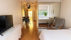 Ein Hotelzimmer mit Bett, Fernseher, Schreibtisch mit Stuhl und Blick ins Freie.
