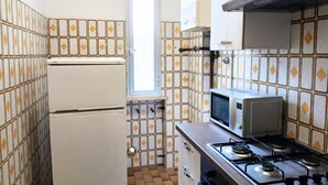 Une cuisine compacte équipée d’un réfrigérateur, d’un four à micro-ondes et d’une cuisinière à gaz.