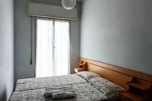 Un dormitorio con cama, ventana con cortinas, aire acondicionado montado en la pared y cabecero de madera.