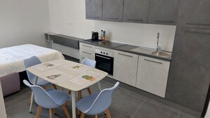 Une cuisine compacte avec un coin repas, comprenant une table avec des chaises, un petit four, un évier et des placards.