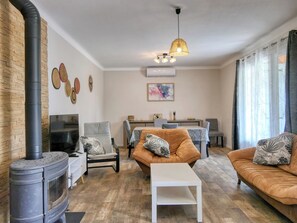 A living room with a fireplace, sofa, coffee table, and dining area. - Maison avec jardin 3 ch entre Alpilles et Luberon (Sénas)