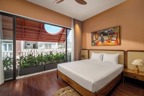 A bedroom with a large bed, a ceiling fan, a painting on the wall, and a view through a sliding door. - The Sage Villa - 5BR Mini Pool and Sauna (An Hai)