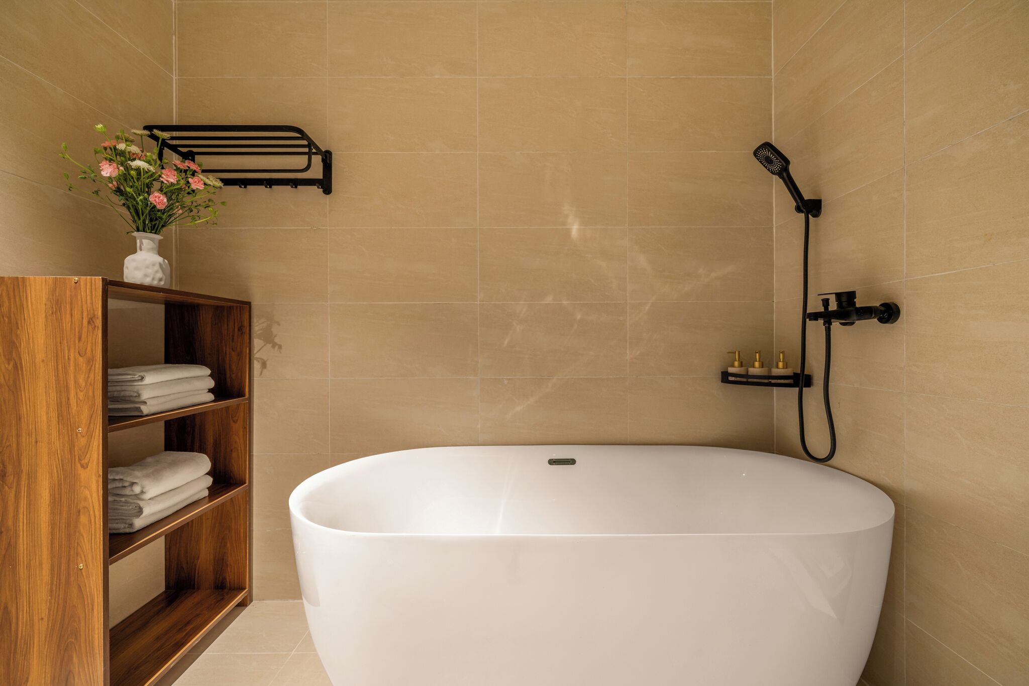 Une salle de bain moderne avec une baignoire sur pieds, une étagère en bois avec des serviettes, un porte-serviettes mural et une douchette à main.