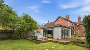 A modern house with a patio, a glass door leading to a room, and a brick exterior. - New! Central 3BR near Kenilworth Castle and A46 (Kenilworth)