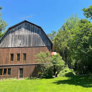 A large wooden barn with a sloped roof, a door, and a small window on the side.