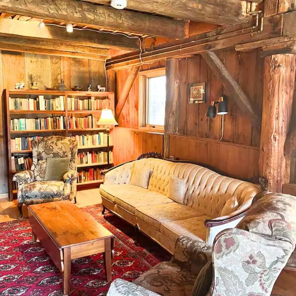 A cozy living room with a sofa, armchair, wooden bookshelf, and a coffee table.