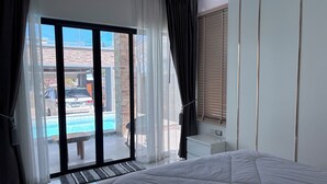 A bedroom with a large bed, a sliding glass door leading to a pool area, and a view of the outside. - Luxury 3-bedroom Pool Villa in peaceful Hua Hin (Hua Hin)