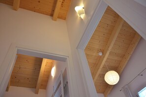 Une pièce avec des poutres en bois, un luminaire au plafond et un lustre suspendu.