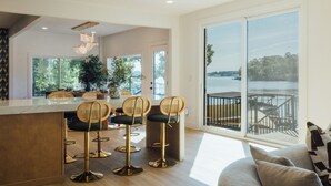 A modern kitchen with a bar area, large windows, and a view of a body of water. - The Superstar | Waterfront Pool & Pickleball (Hot Springs National Park)