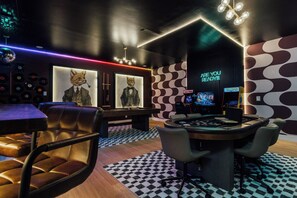 A modern lounge area with leather chairs, a gaming table, and wall art. - The Superstar | Waterfront Pool & Pickleball (Hot Springs National Park)