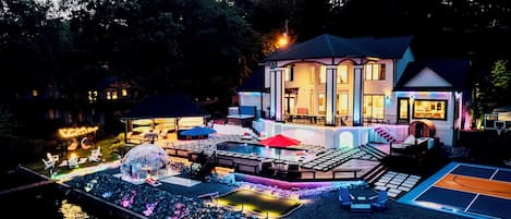 Ett modernt hus med en swimmingpool, utomhusmöbler och ett stort parasoll.