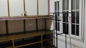 Una habitación con literas, una ventana con persianas, una puerta y un estante.