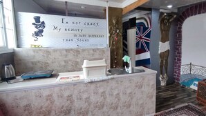 Una cocina con un lavamanos, una cafetera y un televisor.